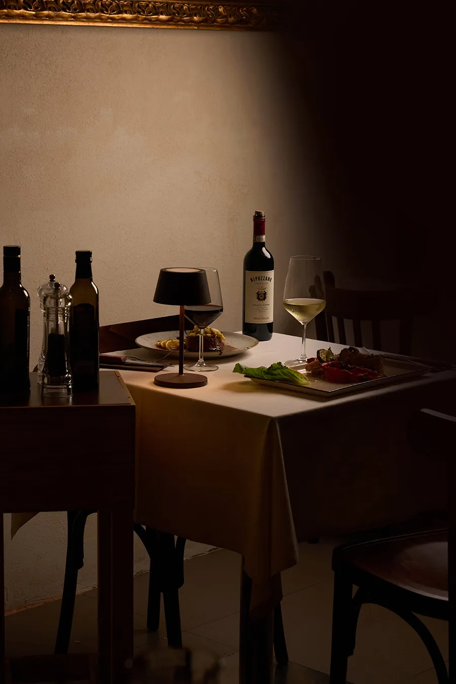 Tavolo con due secondi piatti e due calici di vino all'Osteria dei Medici